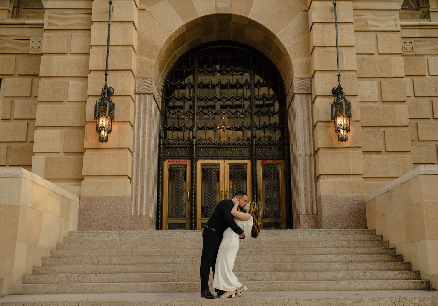 Groom dips bride for a kiss on grand stone steps of historic building in downtown phoenix elopement