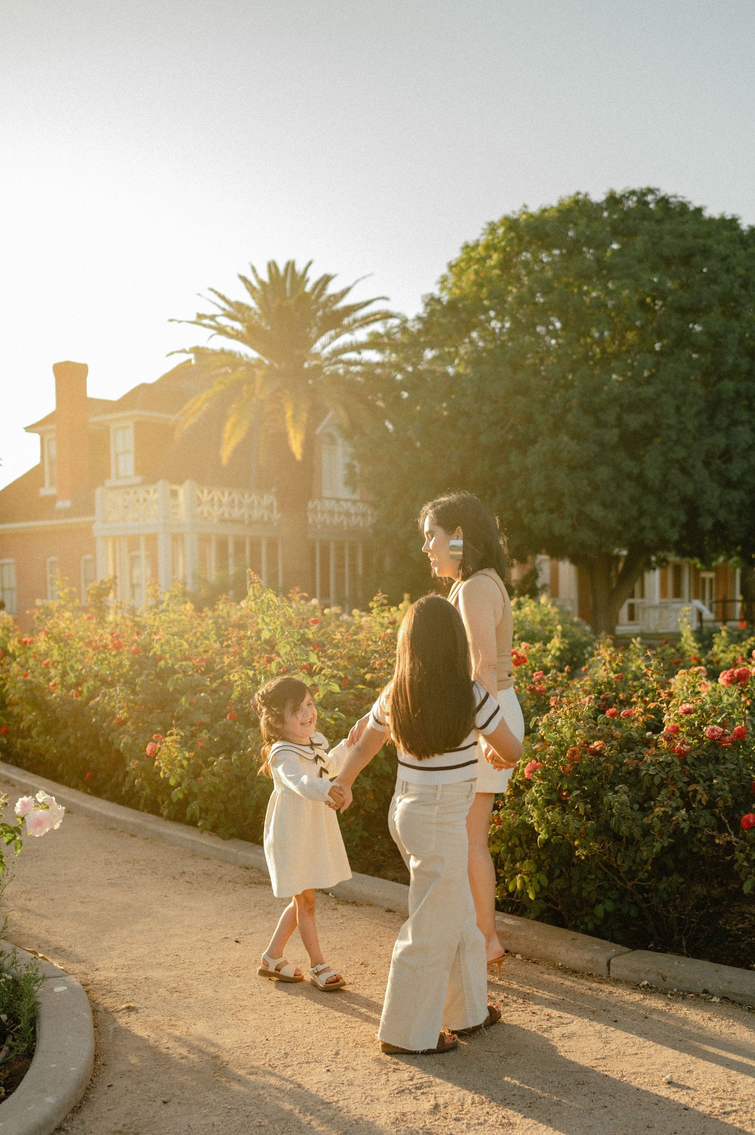 A mother walks hand in hand with her daughters through a rose filled garden at Sahuaro Ranch Park in Glendale, AZ.