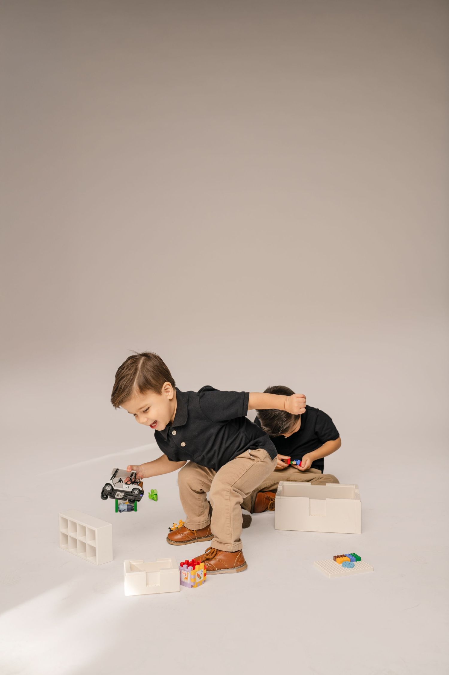 Two young boys play with toy cars during a family photography studio session at Afternoons Studio in Phoenix, AZ.