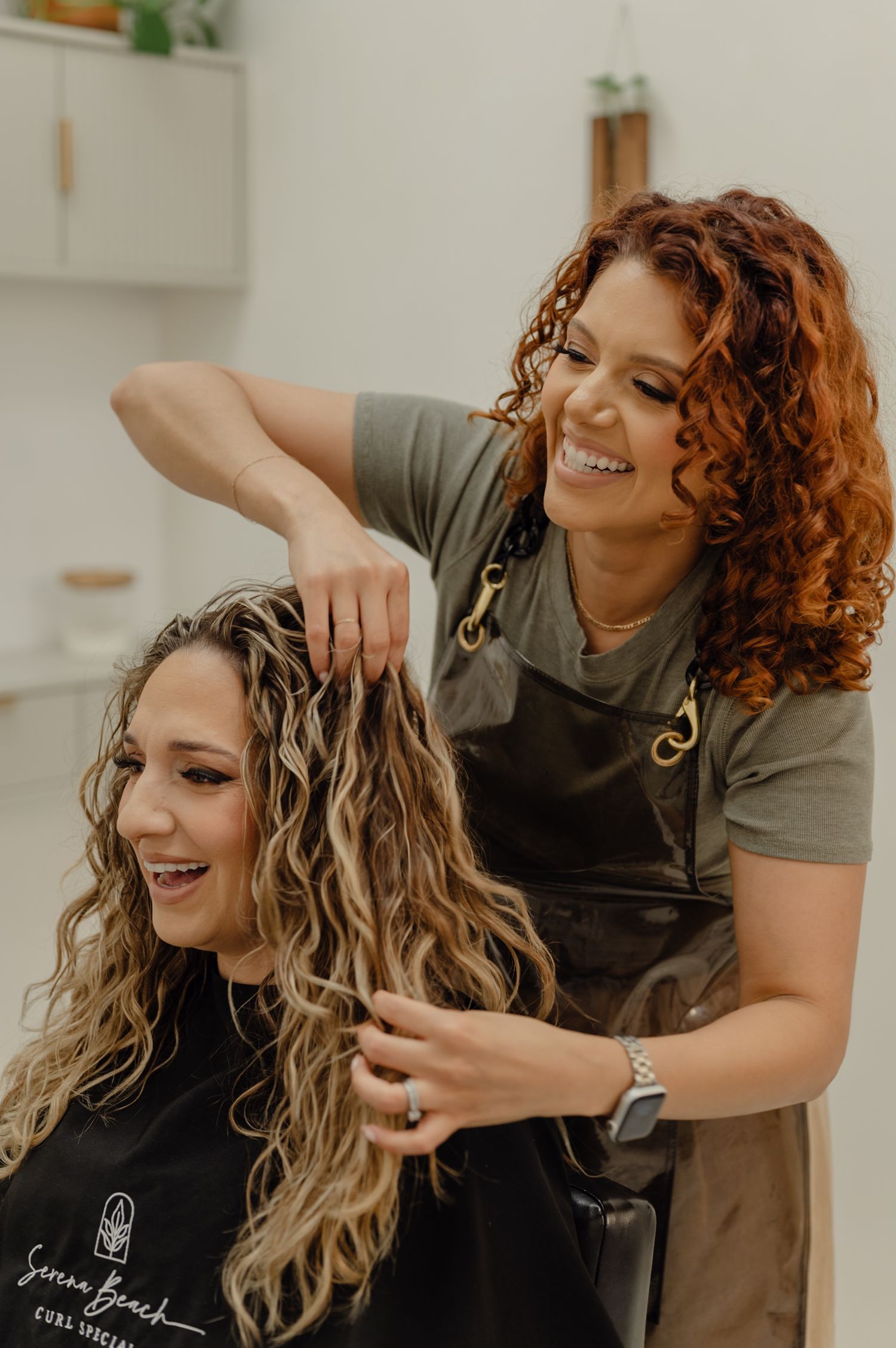 Serena Beach Hair working on curly client in her Peoria salon, showcasing technique and brand presence.