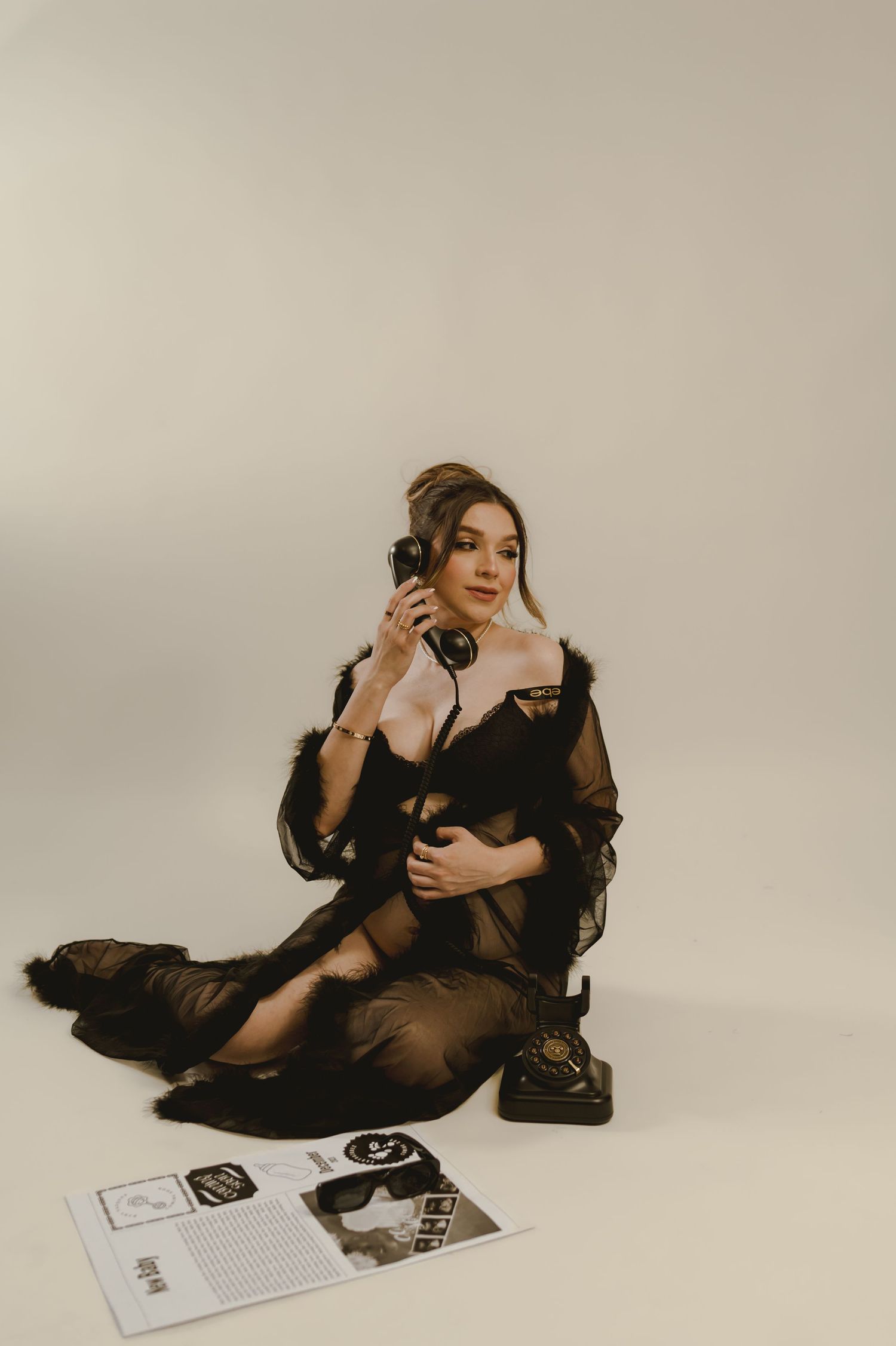 pregnant woman in a sheer black gown poses beside a magazine prop during a phoenix editorial session