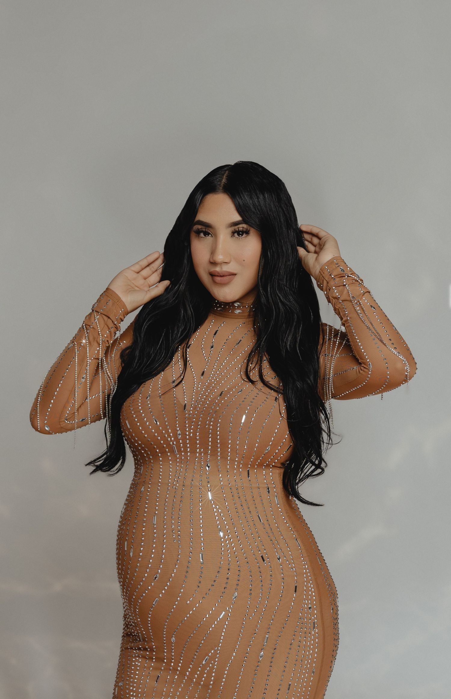 pregnant woman in a sequined gown poses against a soft backdrop during a phoenix studio session