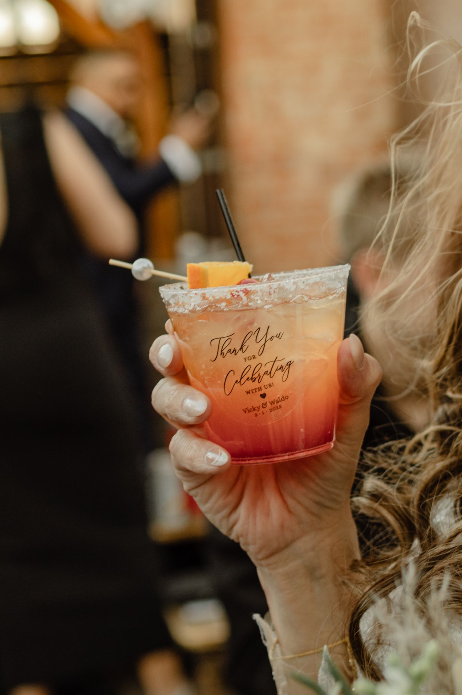 Custom wedding cocktail held during reception, garnished with citrus and rosemary for a personalized guest experience.