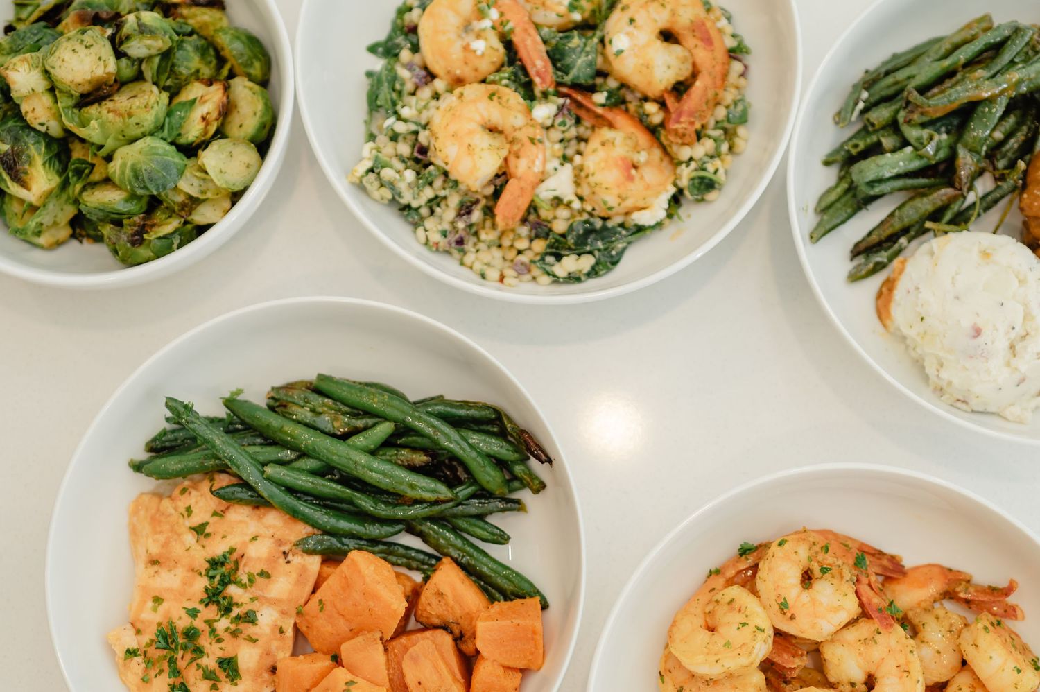 A variety of healthy meals including greens, rice, and proteins laid out in bowls — clean eating visual.