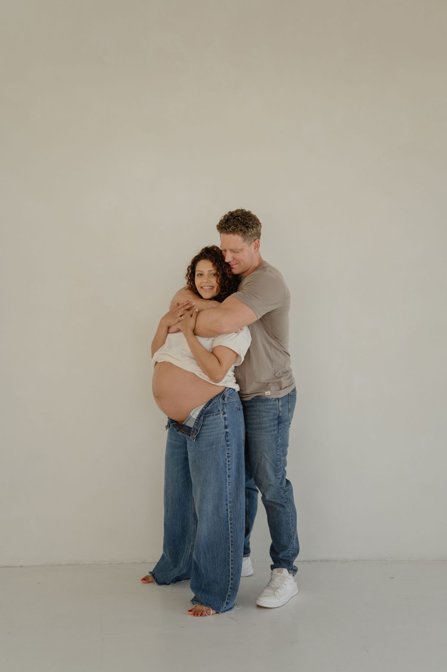 couple embraces while cradling the bump during a phoenix studio maternity session