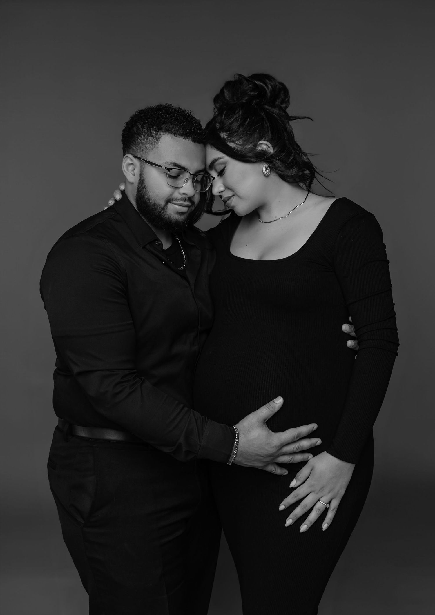 expecting couple embraces in matching black outfits during a phoenix studio maternity session