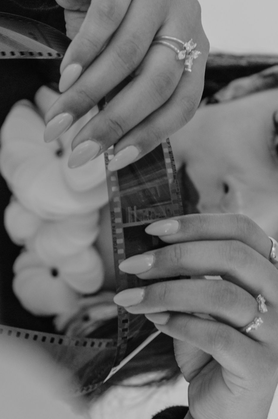 Black-and-white close-up of hands adjusting boutonnière flowers — cinematic and emotional detail shot.