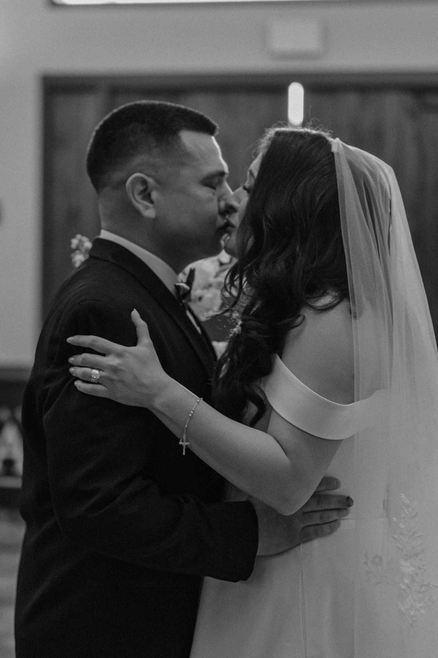 Black-and-white photo of bride and groom sharing emotional first dance, soft lighting and close embrace.