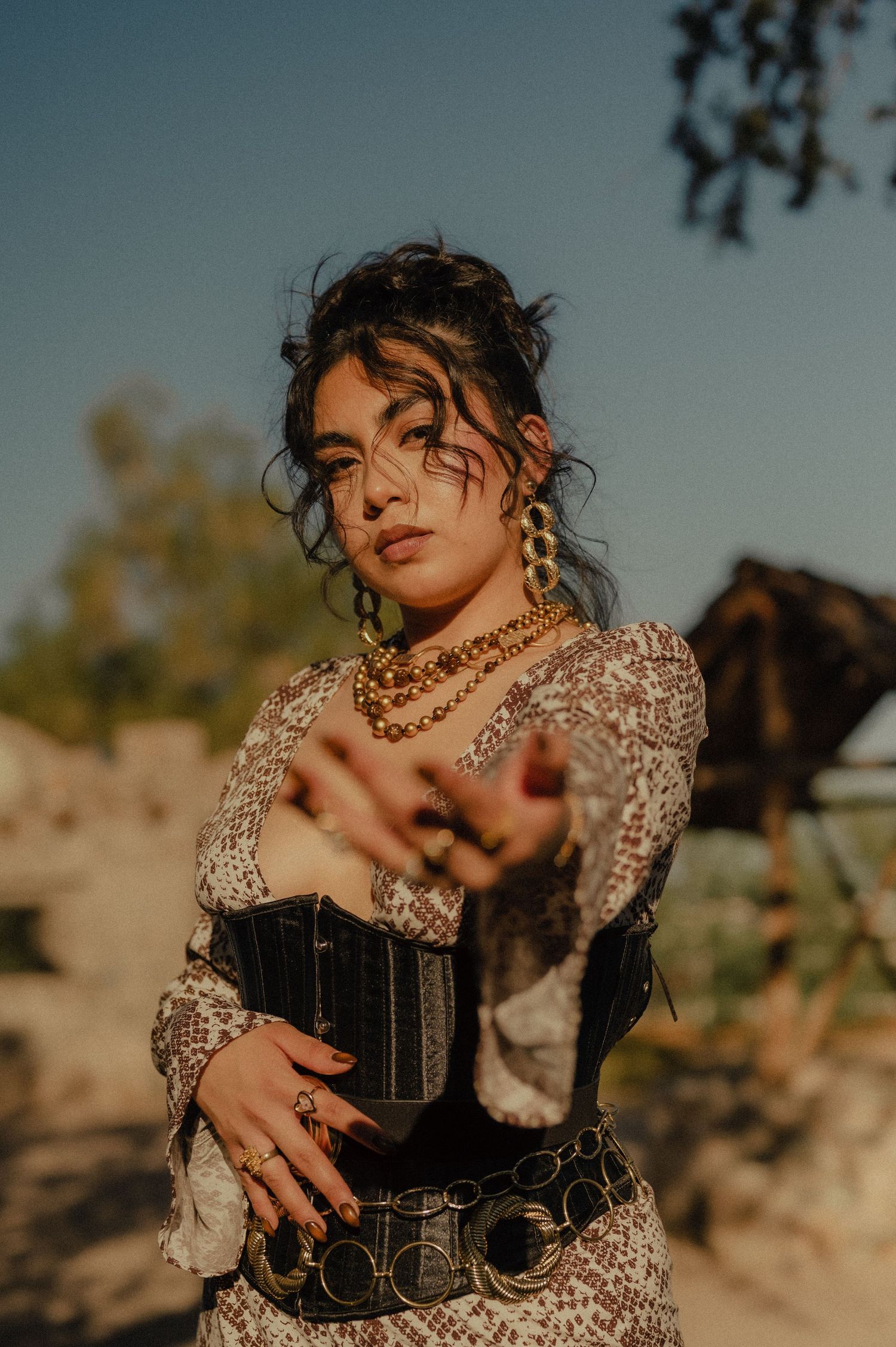 Bold fashion portrait of woman in desert setting wearing corset and layered jewelry.