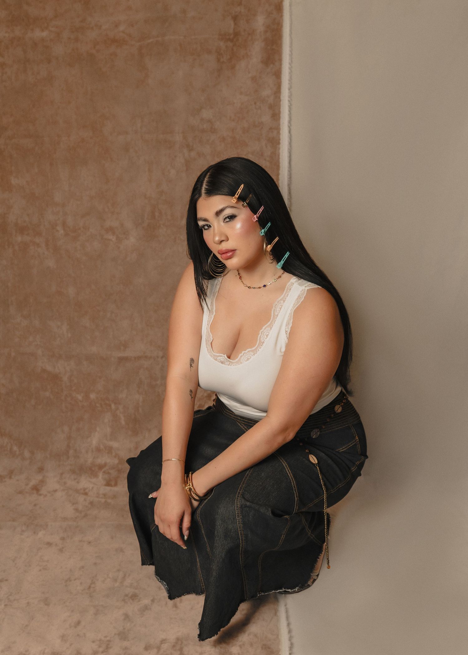 Studio portrait of woman in black pants and white top against neutral backdrop.