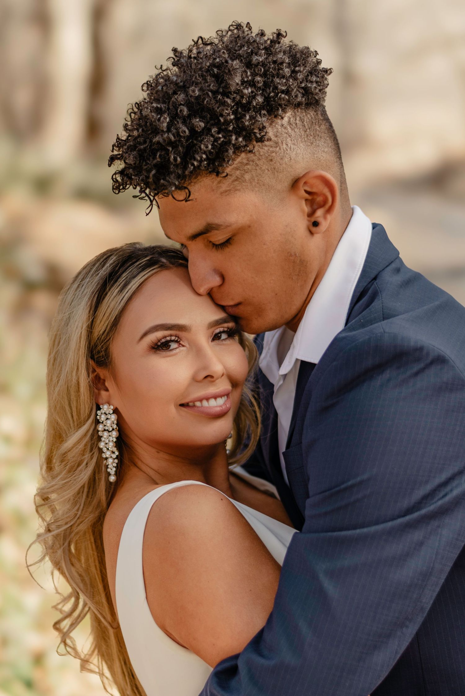 Couple embraces outdoors, with groom gazing down lovingly at the bride.