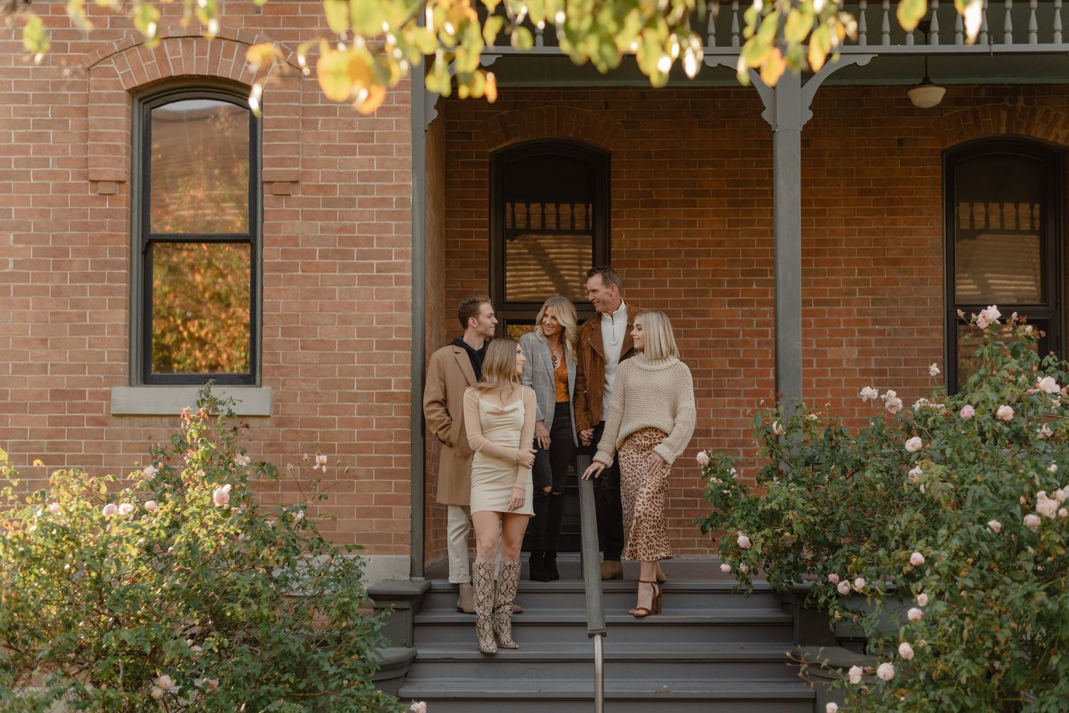 family of five gathers on a brick porch surrounded by roses at heritage square in phoenix