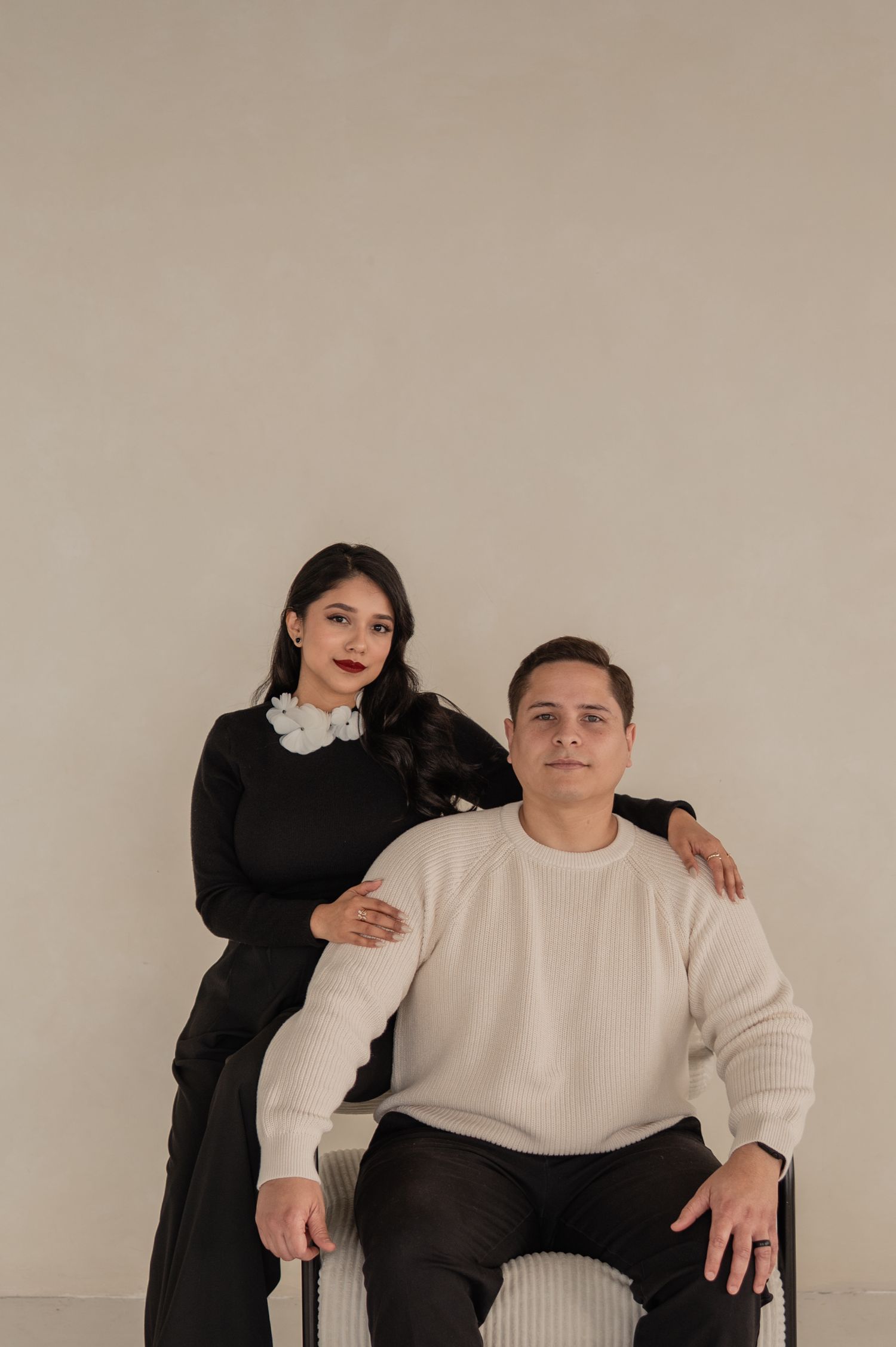 Seated portrait with woman resting hand on man's shoulder — connection and creative partnership.