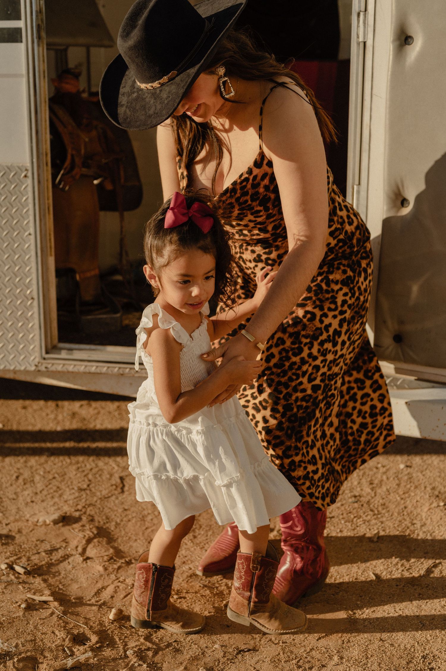 Liz, founder of Hermosa Esthetics, helps her daughter into her boots during a family session.