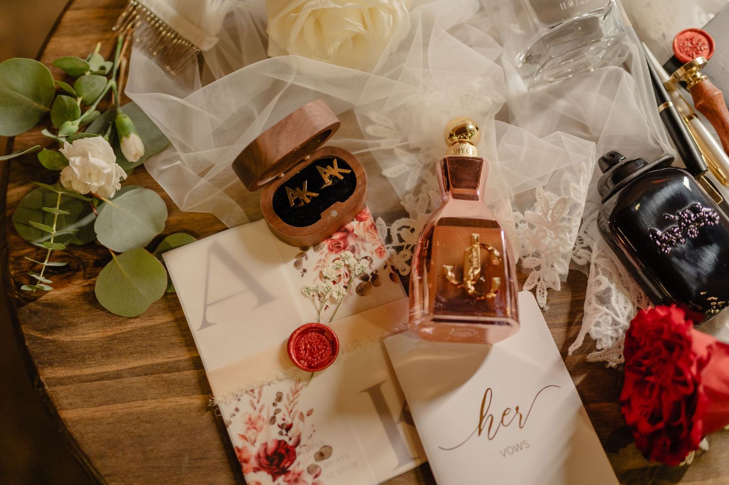 Bride’s flat lay includes perfume, vow books, veil, and floral accents.