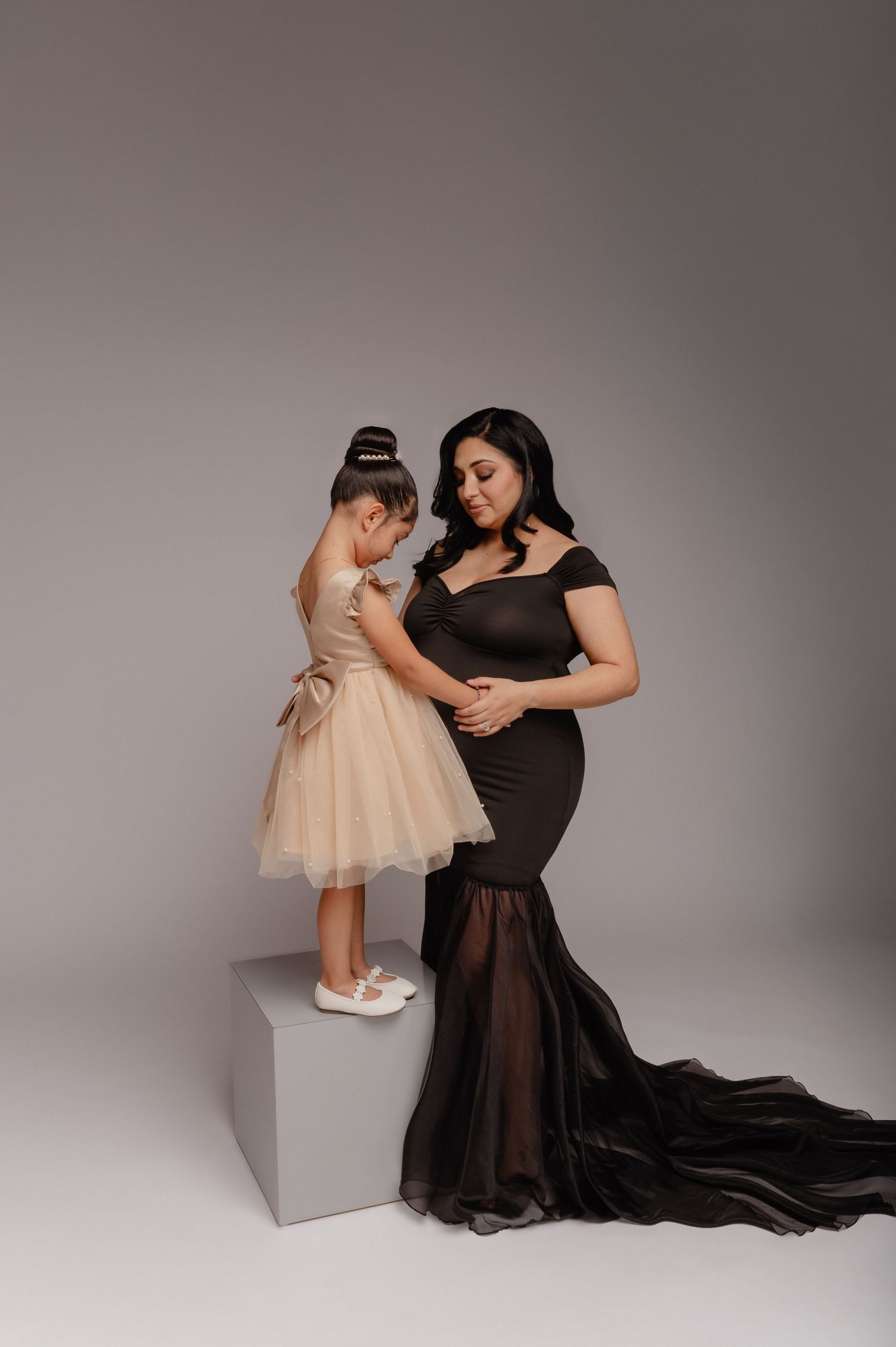 mother and daughter pose together in black and cream gowns during a phoenix studio maternity session