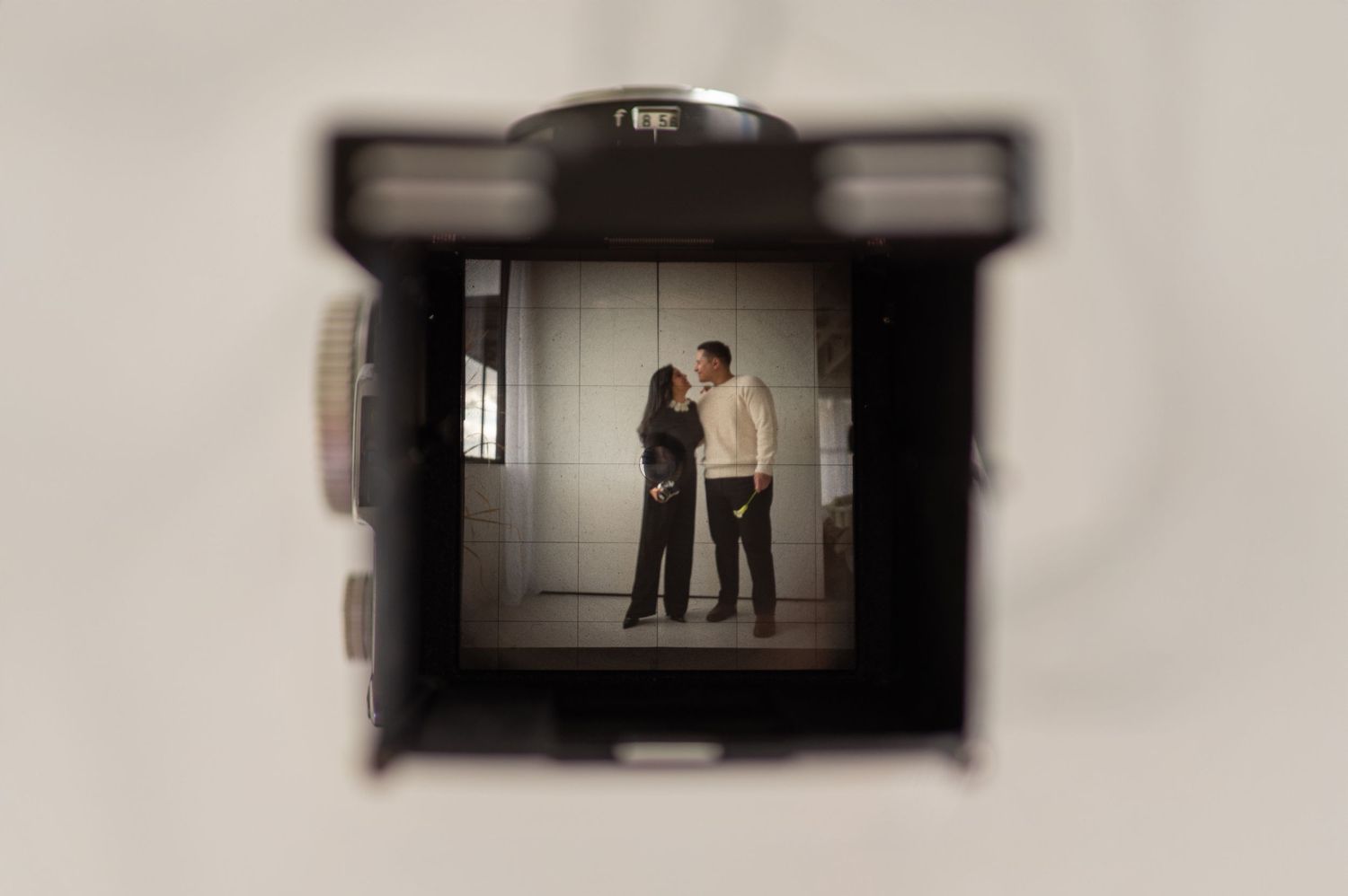 Through-the-lens view of a couple framed in a vintage camera — cinematic storytelling concept.