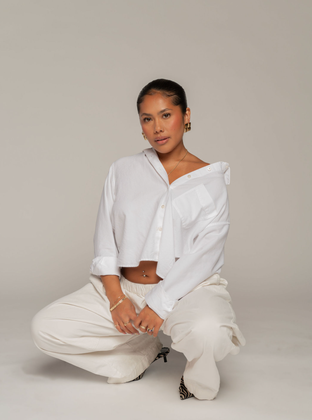 Woman in a white shirt and cream pants kneeling in a Phoenix brand photography studio session
