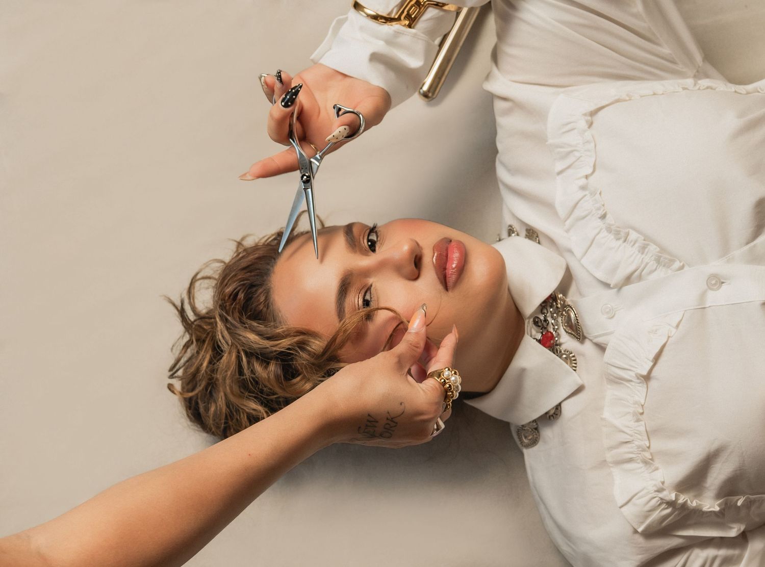 Salon-inspired brand portrait of a woman lying down holding scissors, captured during a beauty branding session.