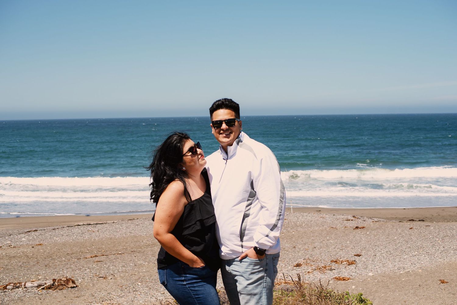 Sharom Rosas, founder of Shamari Visuals, and her husband smiling together on the beach, personal photo.