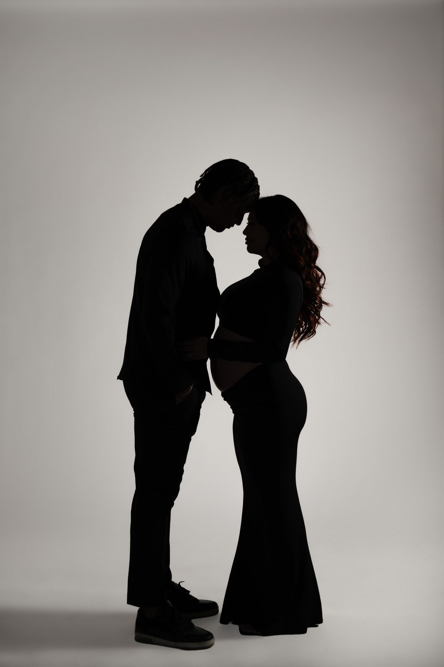 expecting couple stands forehead to forehead in a dramatic silhouette during a phoenix studio maternity session