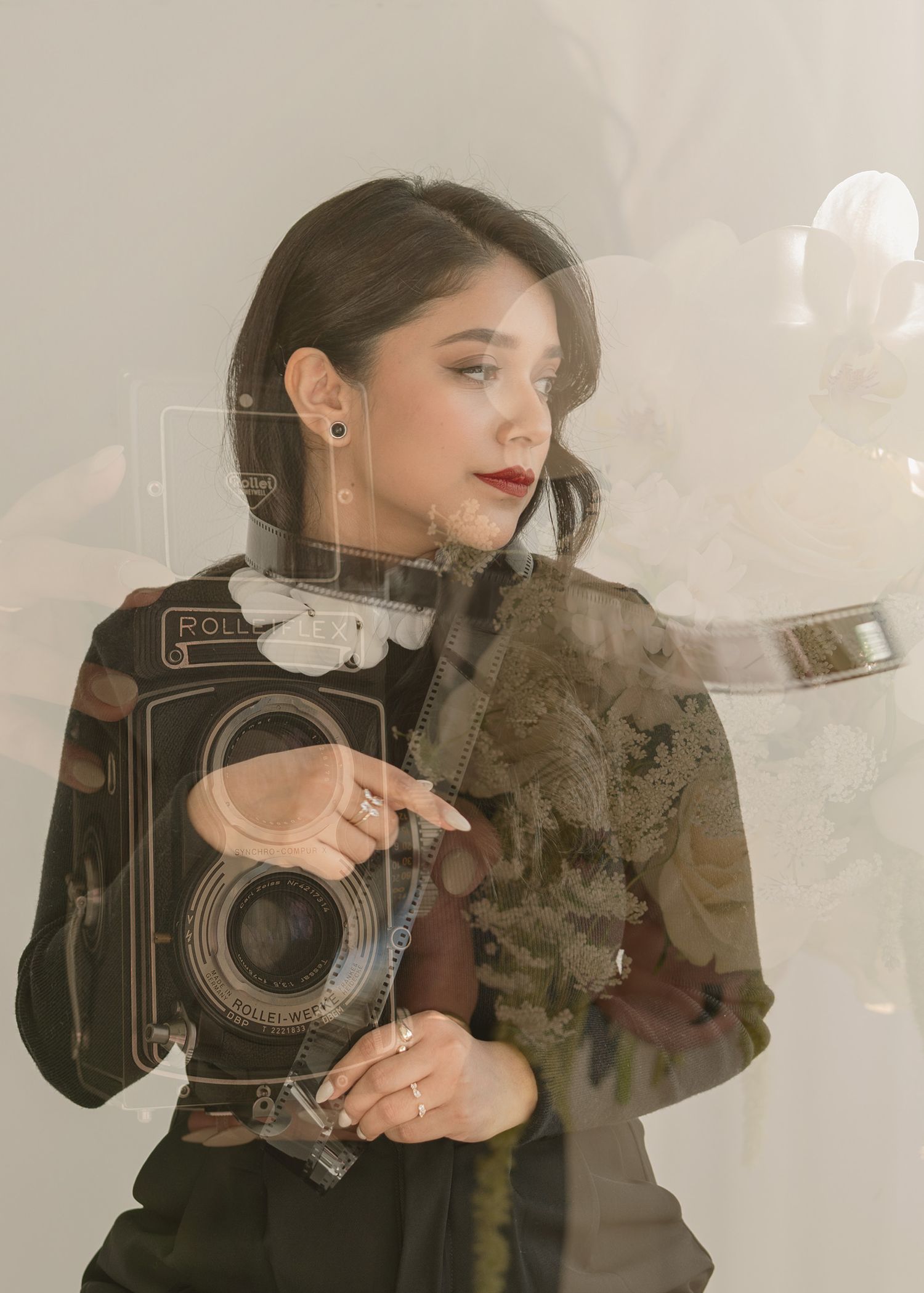 Close-up of a vintage camera surrounded by white and blush florals — warm, romantic still life.