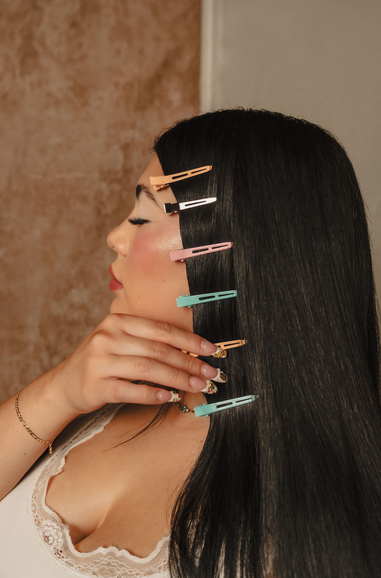 Back view of a woman with long sleek hair styled in rollers — behind-the-scenes salon prep shot.