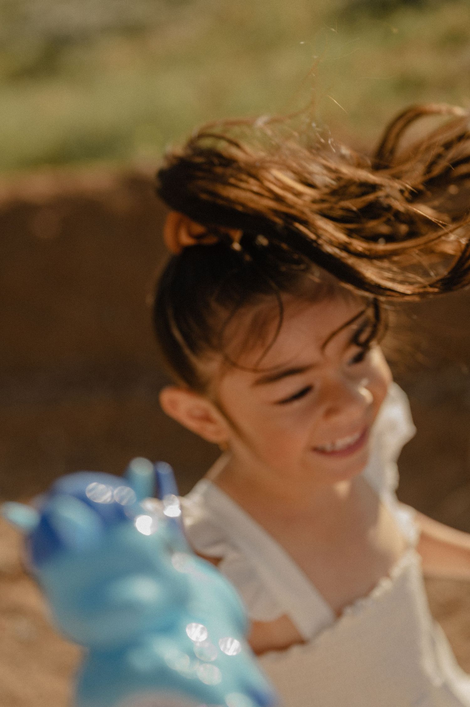 Liz's daughter laughs with windswept hair, a candid moment from their family photography session.