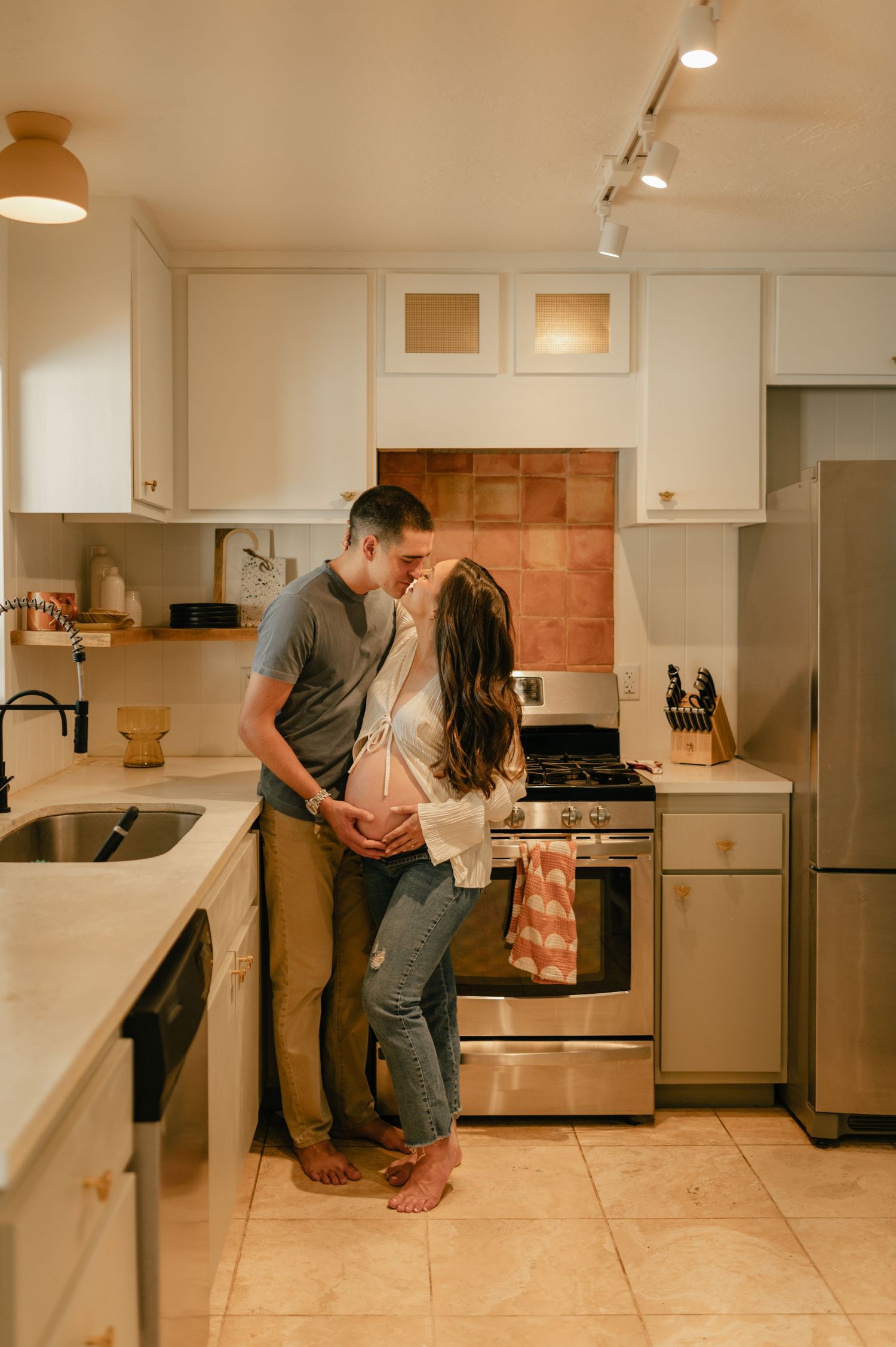 expecting couple embraces in their kitchen during an in-home maternity session in phoenix