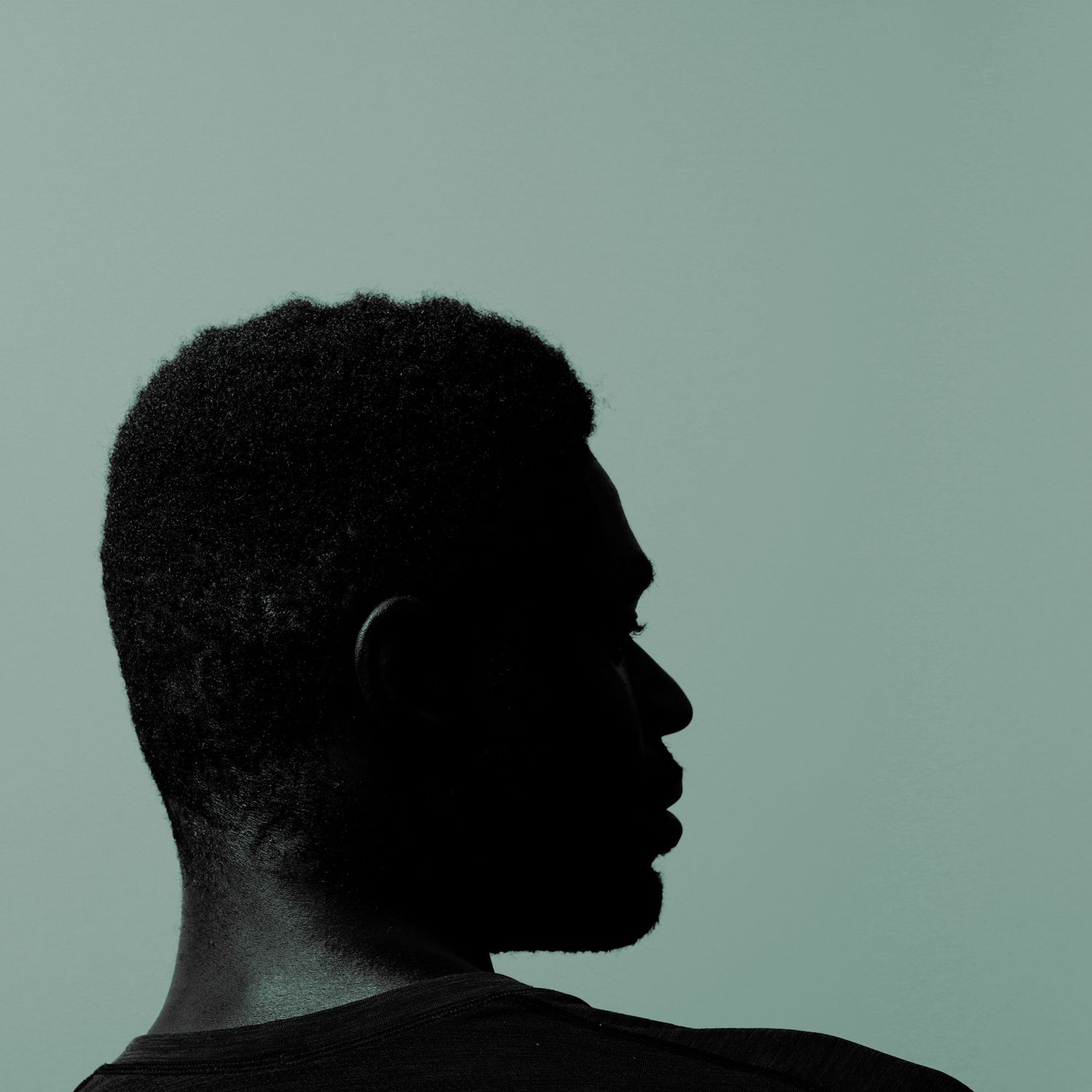 Silhouette of a person with natural hair against a muted teal background, profile view facing right.