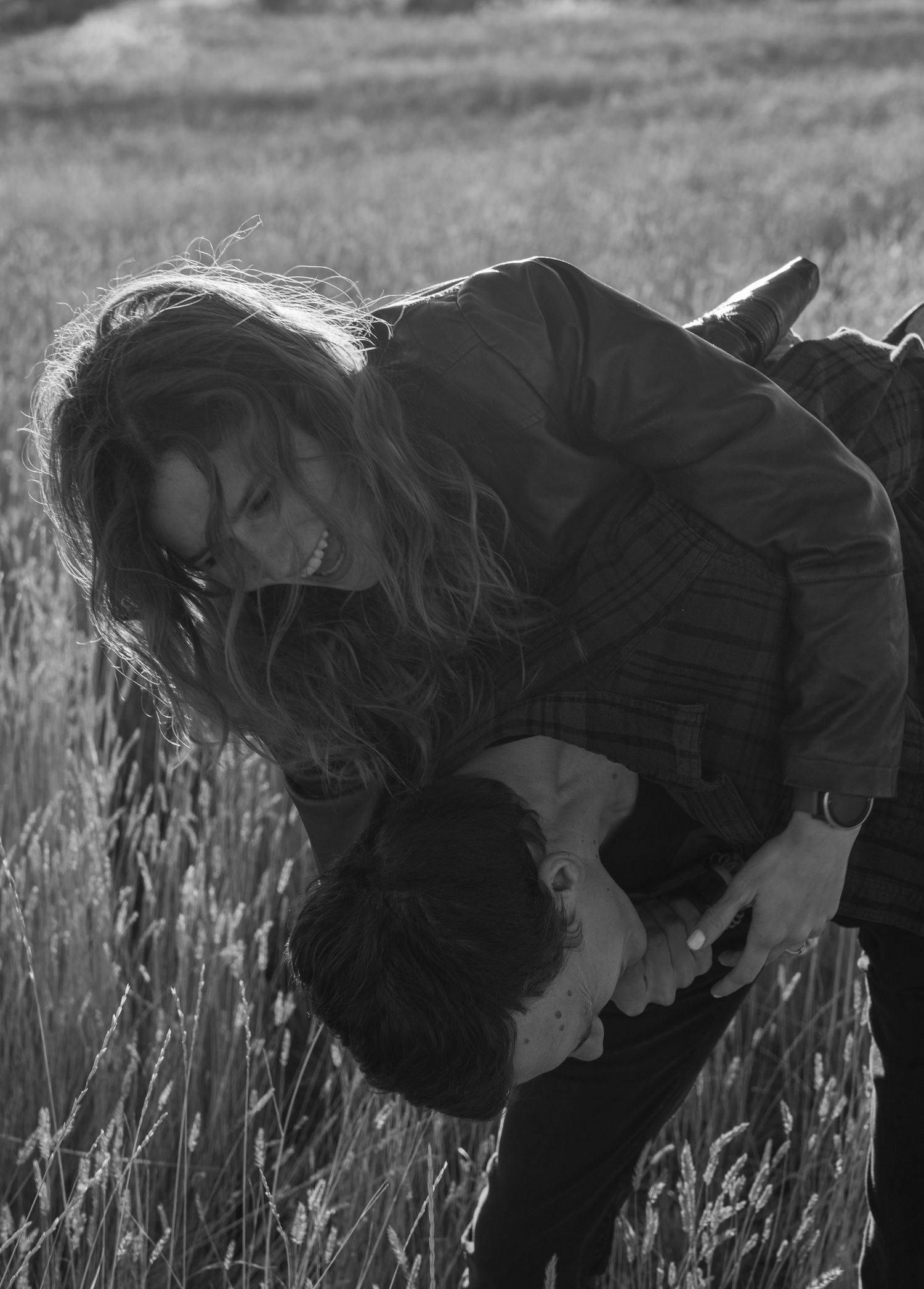 Black and white series of silhouettes bending down in a wheat field during golden hour.