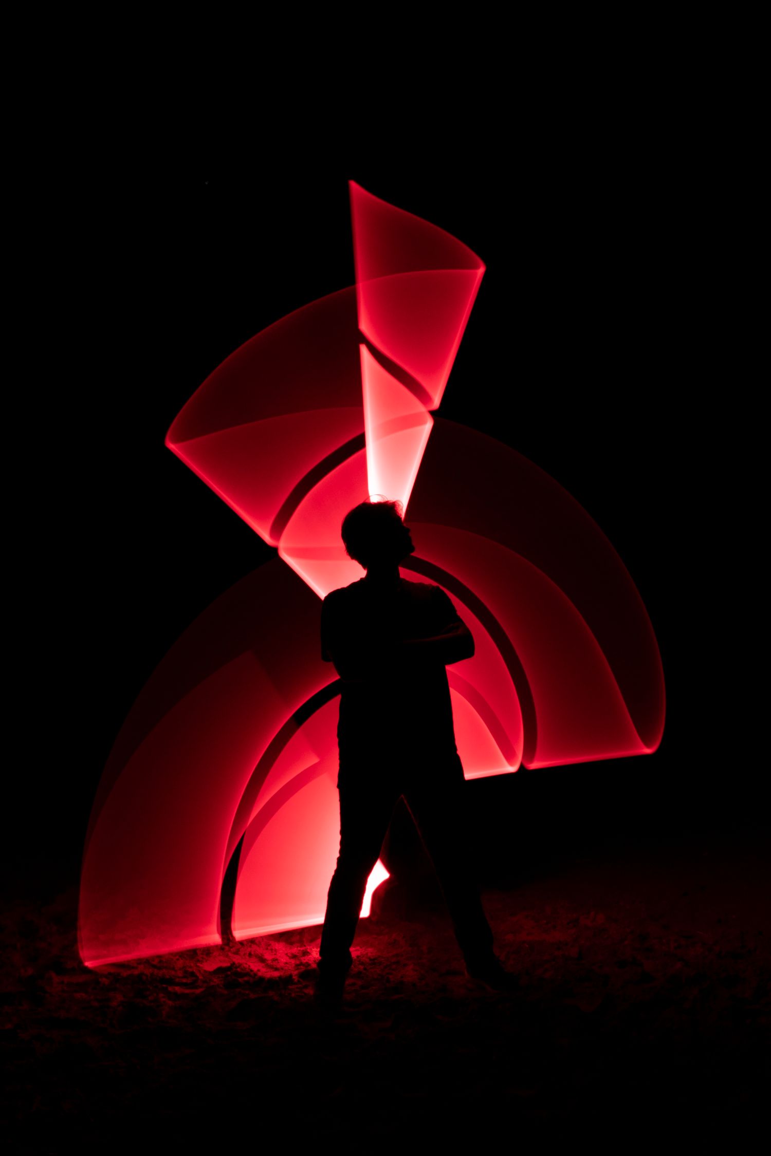 Dramatic red light painting creating geometric patterns against a black background.