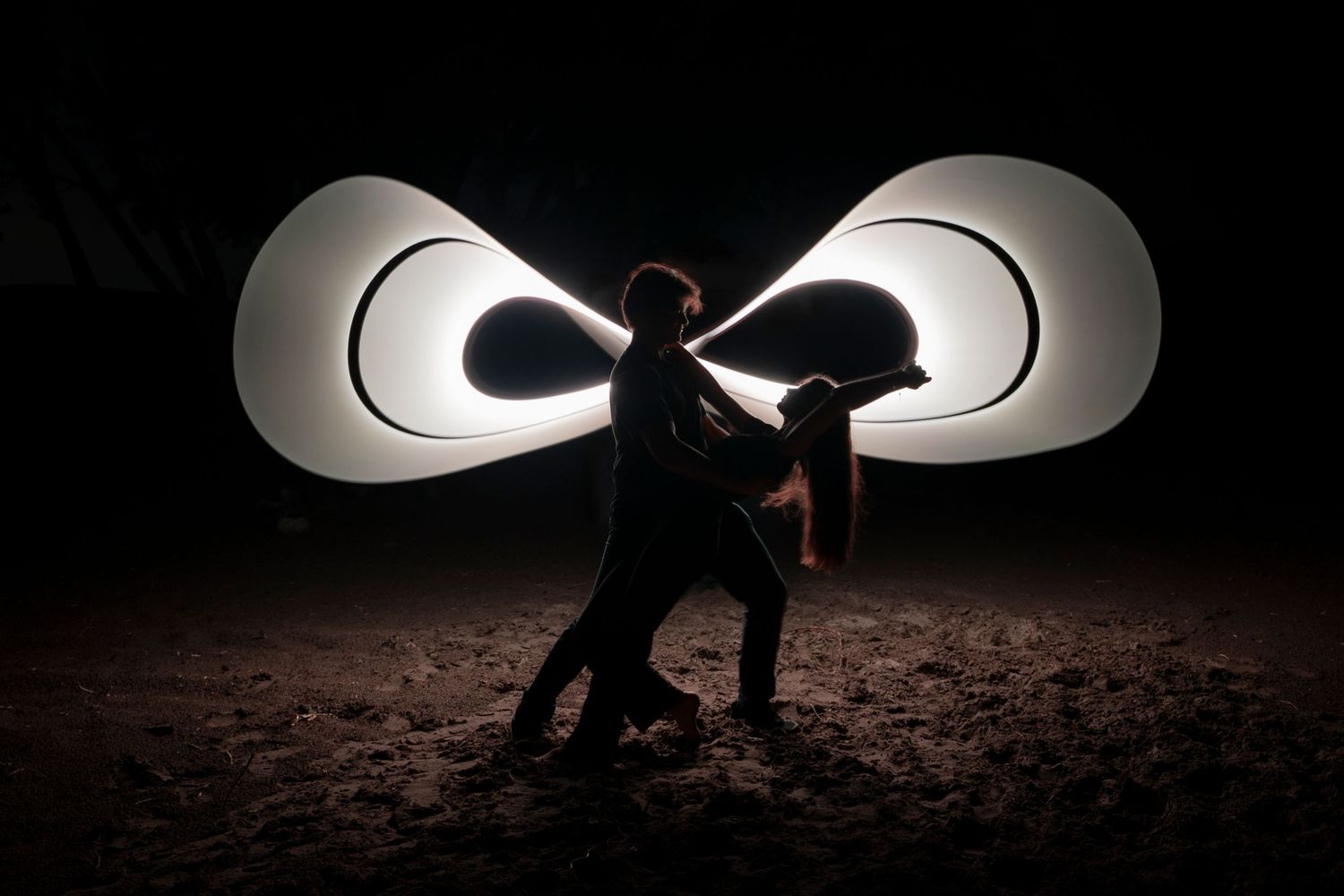 A series of silhouetted figures against bright lights creating dramatic shadows in a dark environment.
