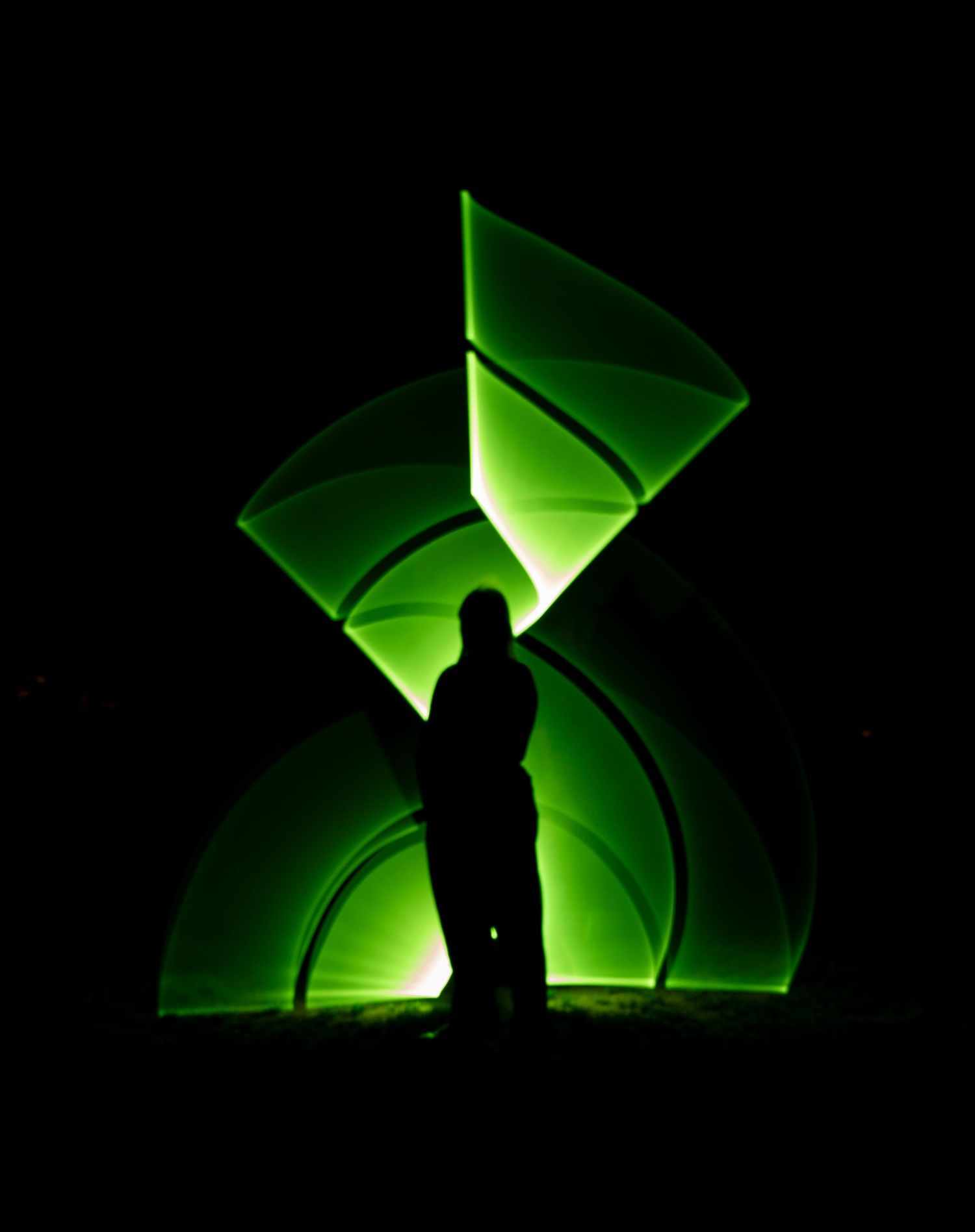 Silhouette against bright green geometric light shapes in darkness.