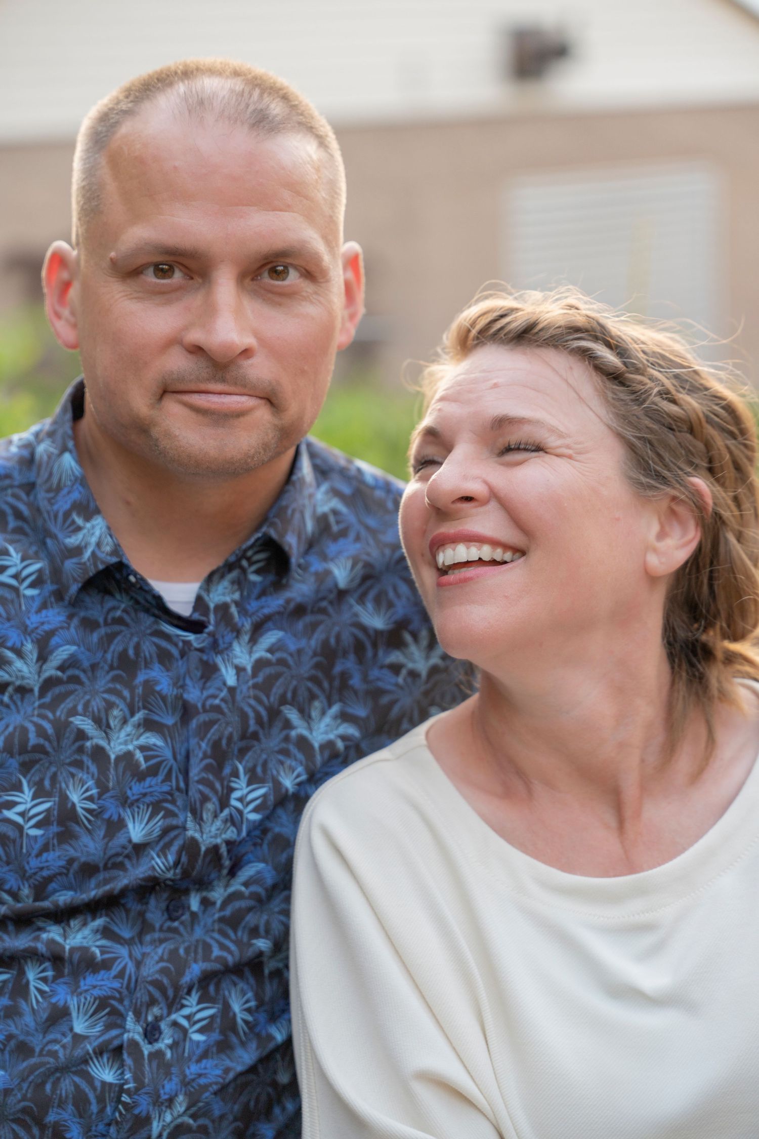 Happy couple sharing intimate moments outdoors wearing blue floral and white outfits.
