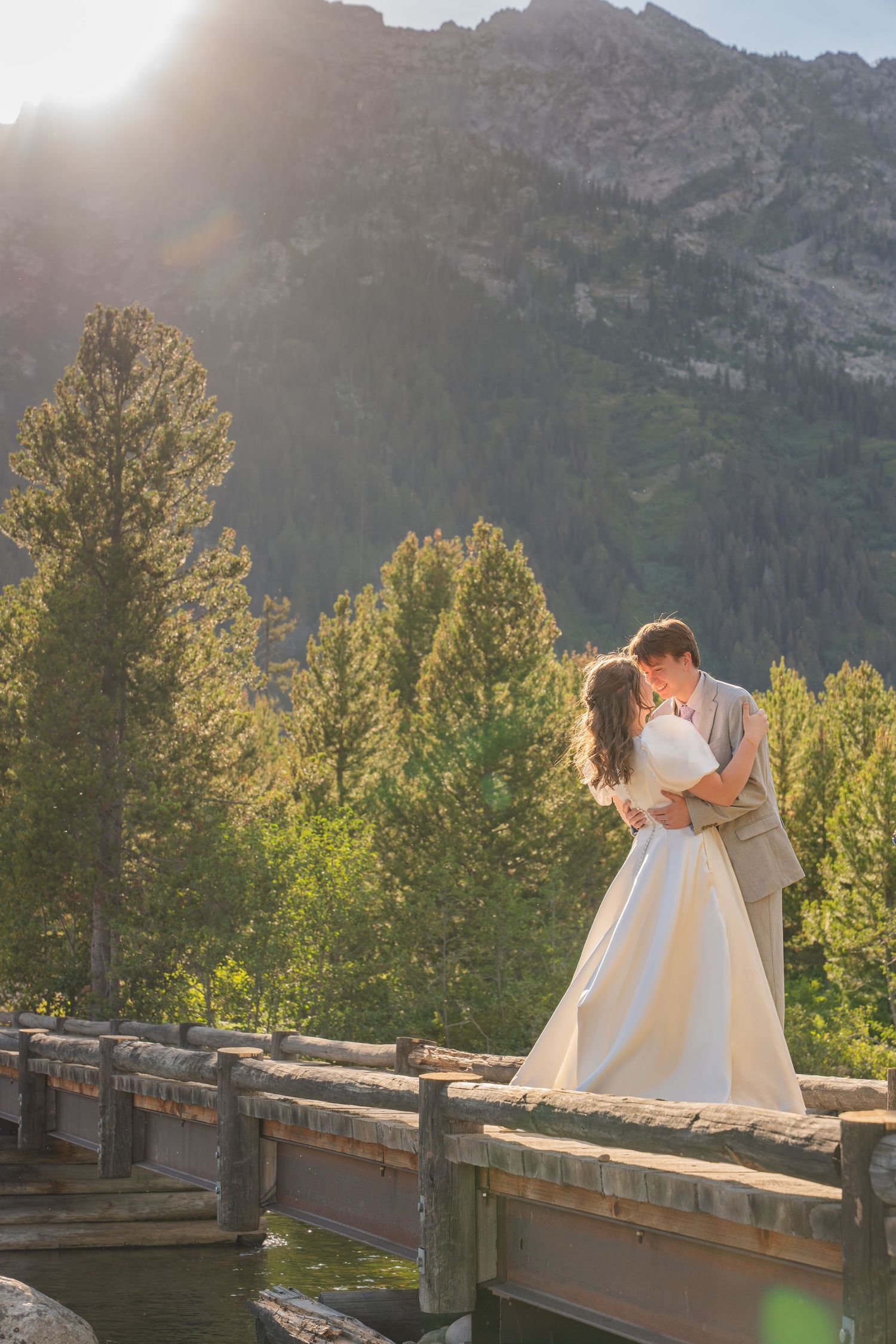 A couple sits together on a wooden deck with majestic mountain peaks in the background.