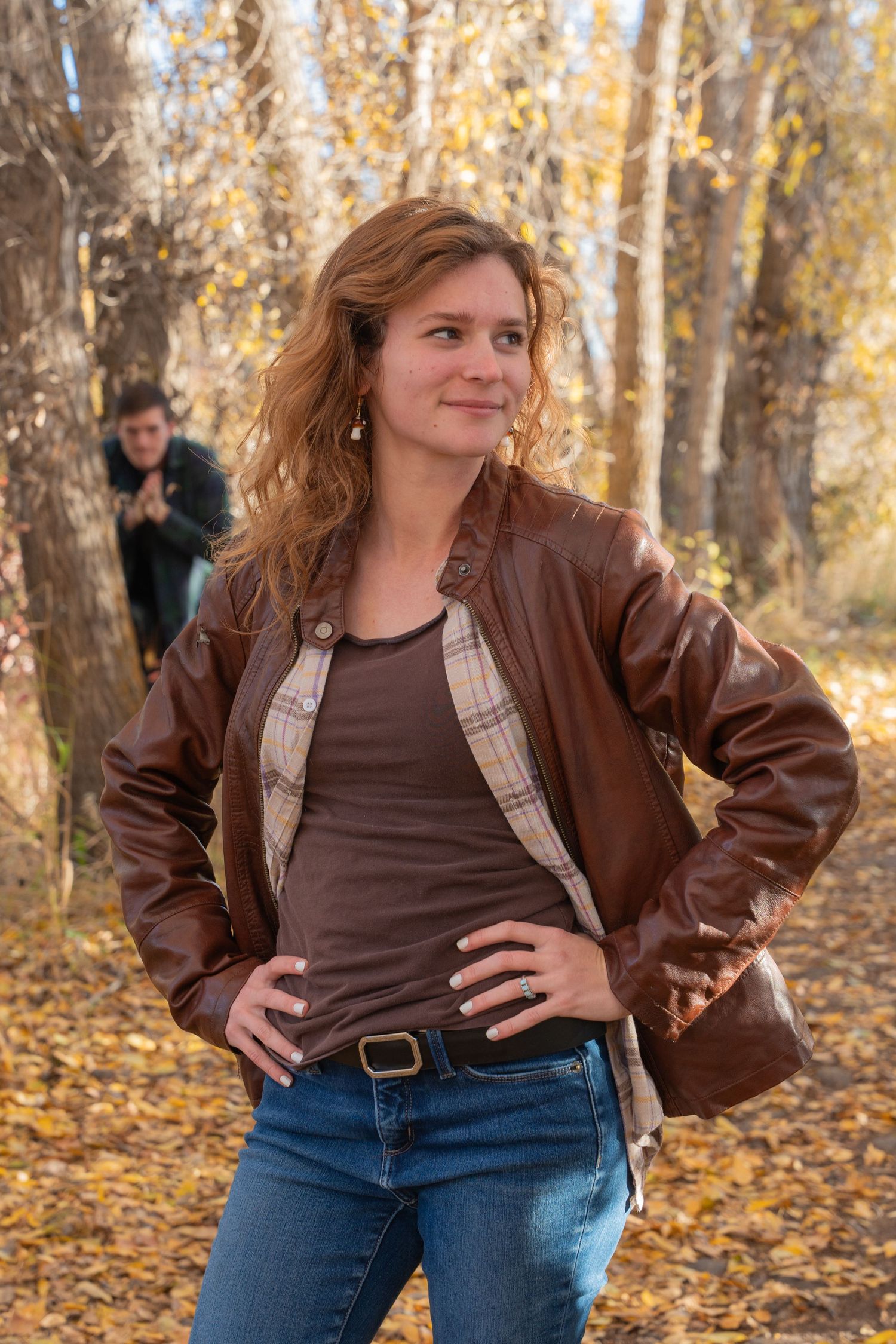 Fashion portraits in brown leather jacket against autumn forest backdrop.