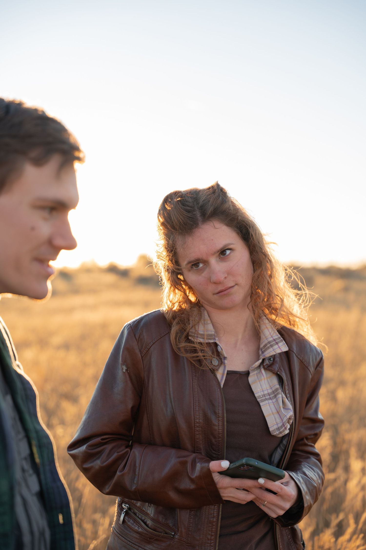 Candid moments captured in warm sunlight as two people interact in casual autumn attire.