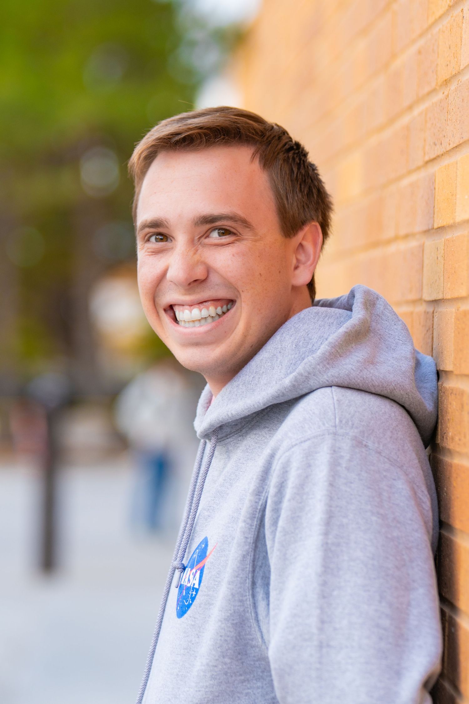 Sequence of casual portraits showing genuine smiles against orange brick wall.