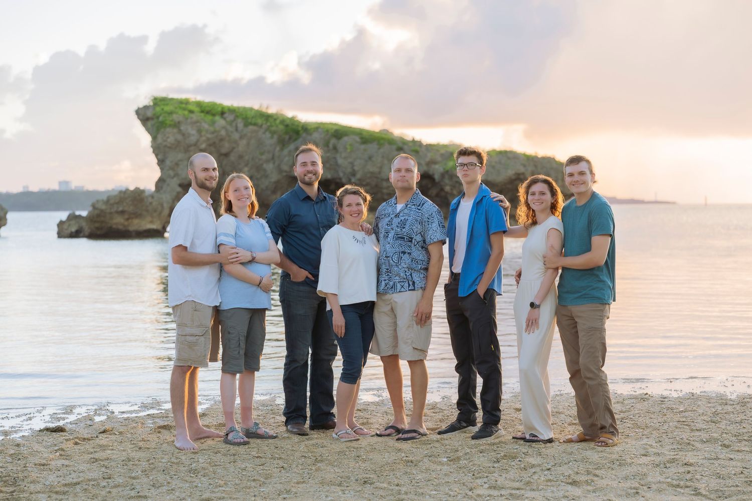 Large group gathering on beach during golden hour.