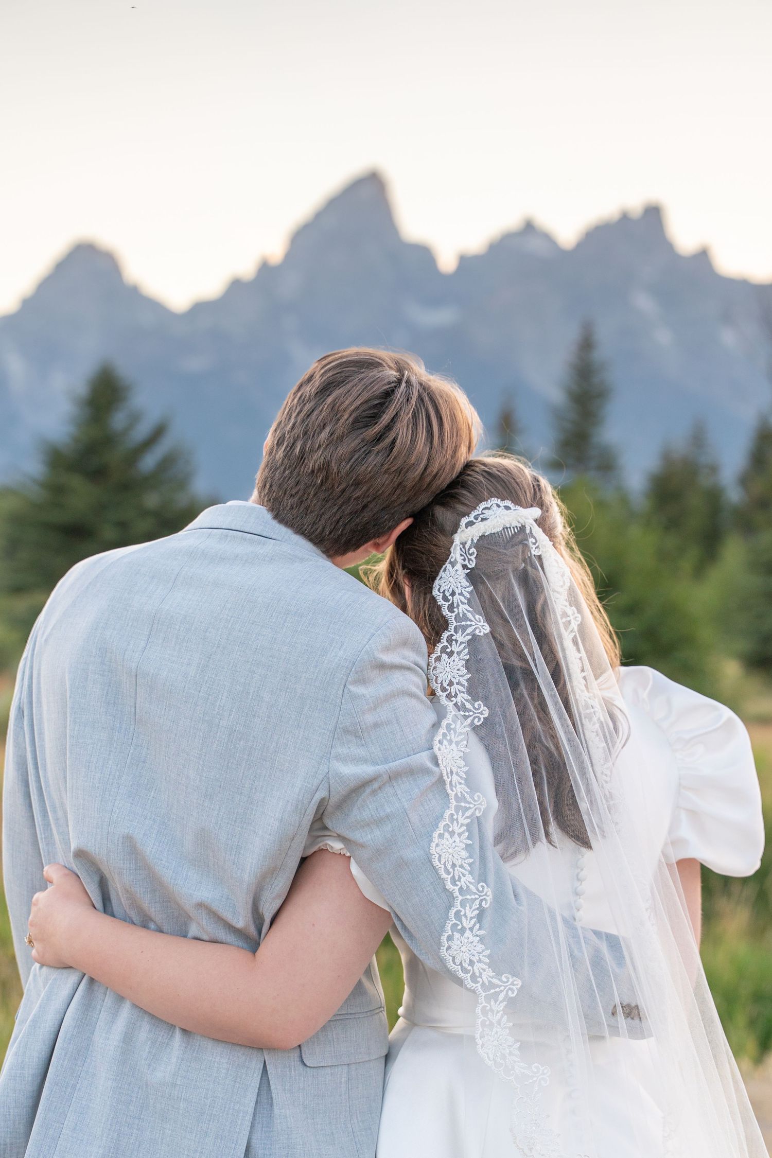 Couple shares romantic moment with mountain peaks silhouetted in background.