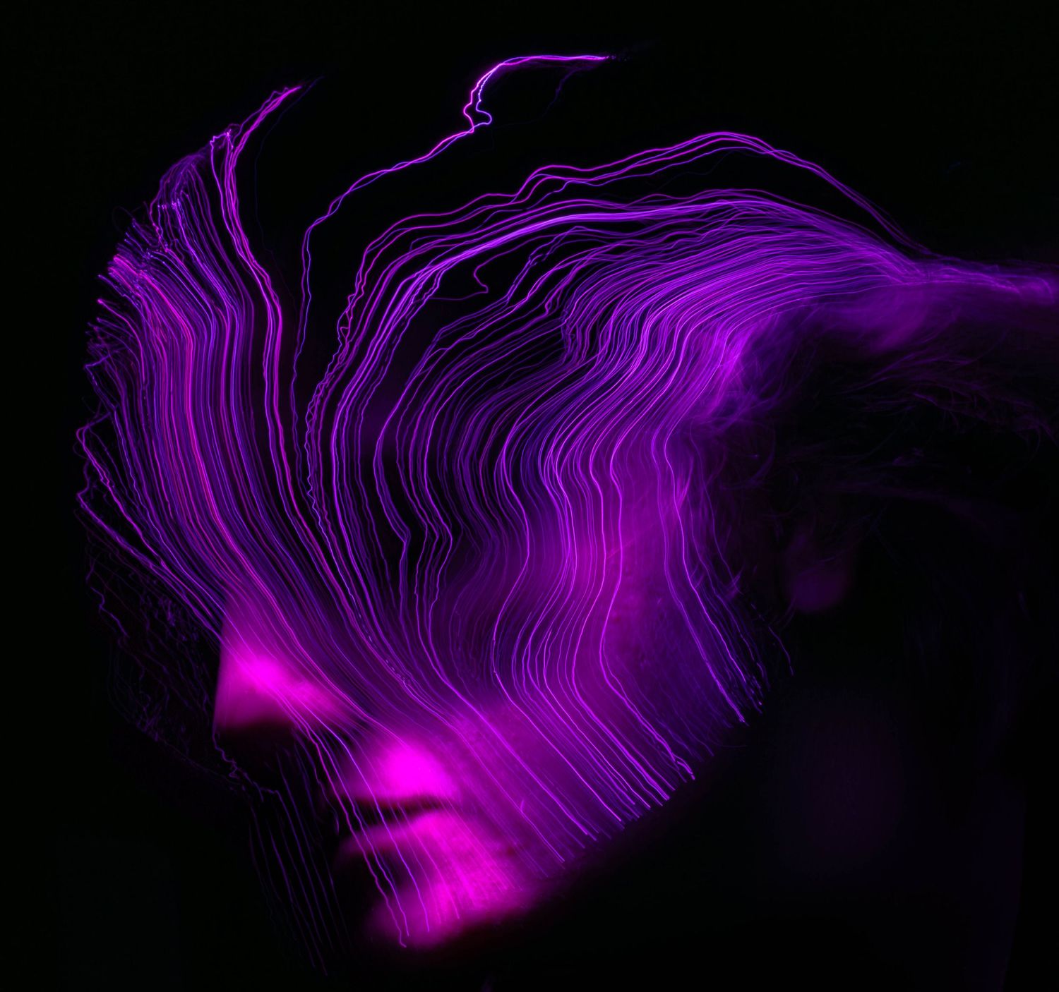 Purple light trails form wavy patterns in a dark environment.