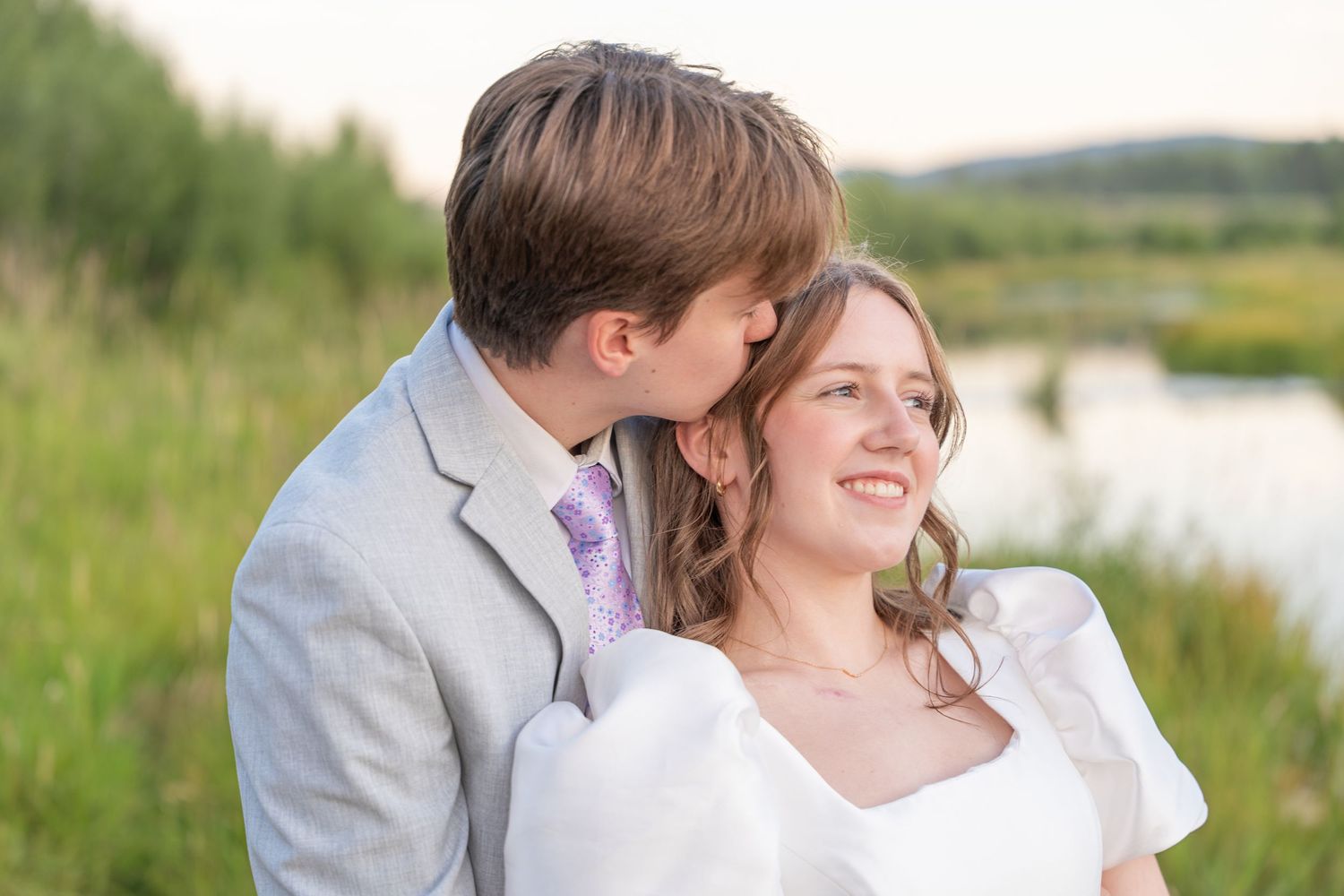 An intimate moment between a bride and groom against a scenic mountain landscape at sunset.