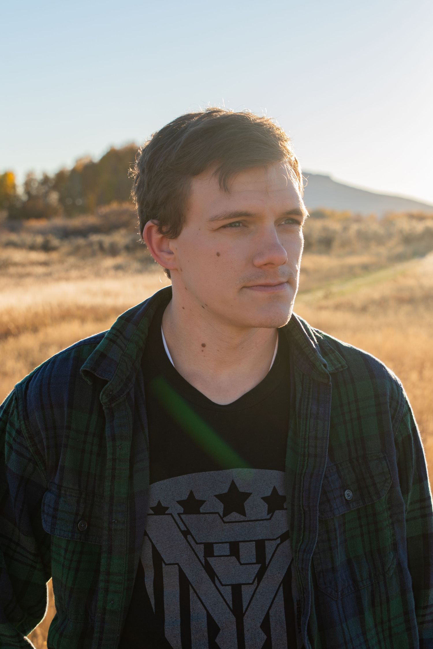 Outdoor portrait series at sunset wearing plaid shirt with graphic design.