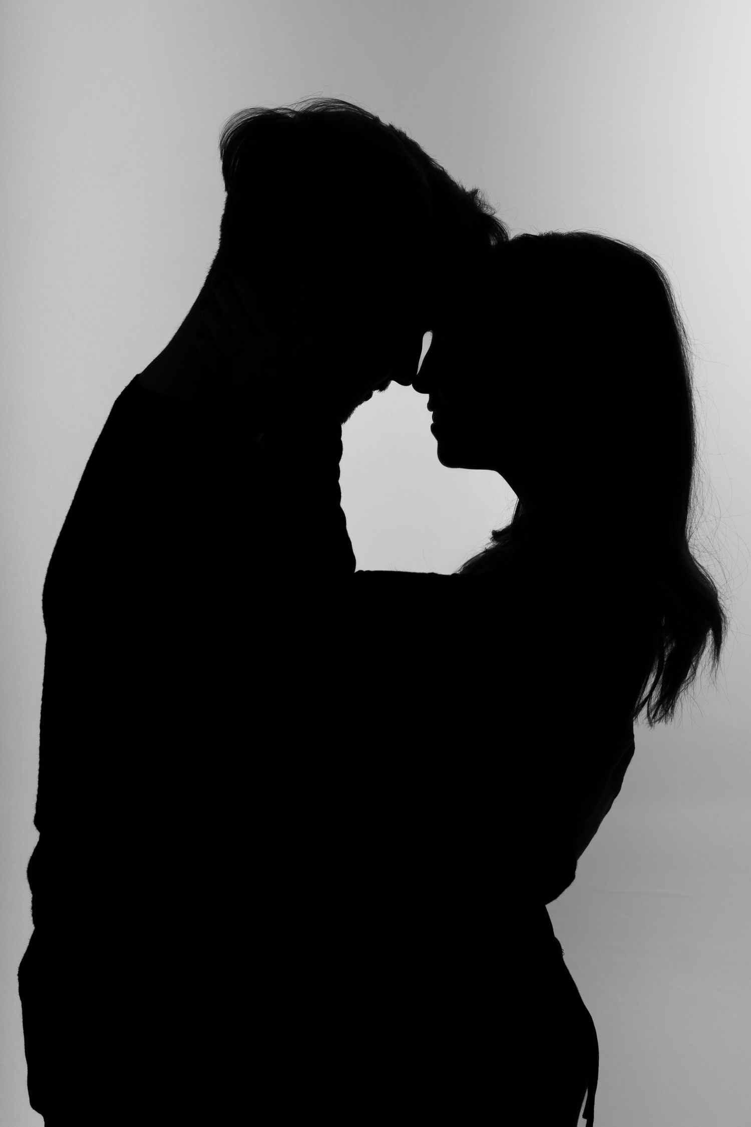 A romantic silhouette portrait shows a couple in an intimate pose against a light background.