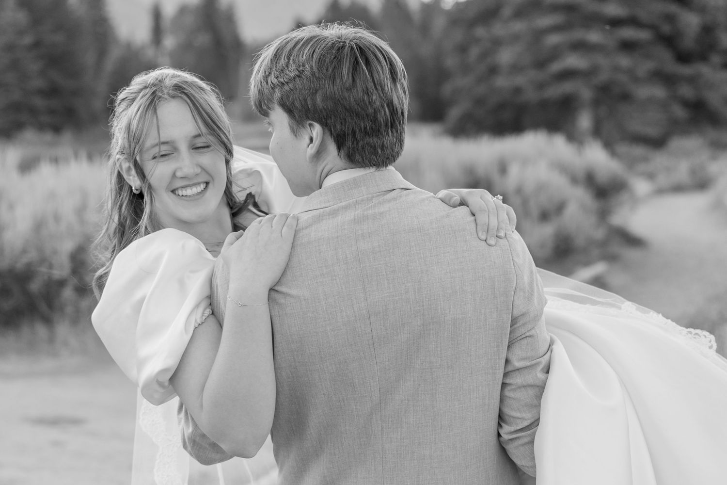 A joyful couple shares a tender moment in black and white photography.