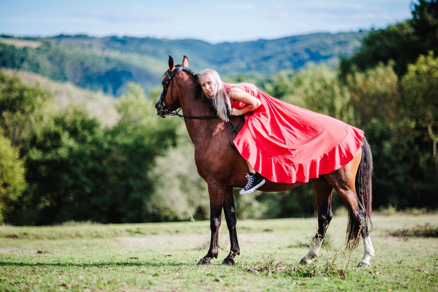 Cavalière en robe rouge sur son cheval. Esthétique noble et liberté, photographe de prestige pour vos projets de mariages en Auvergne.