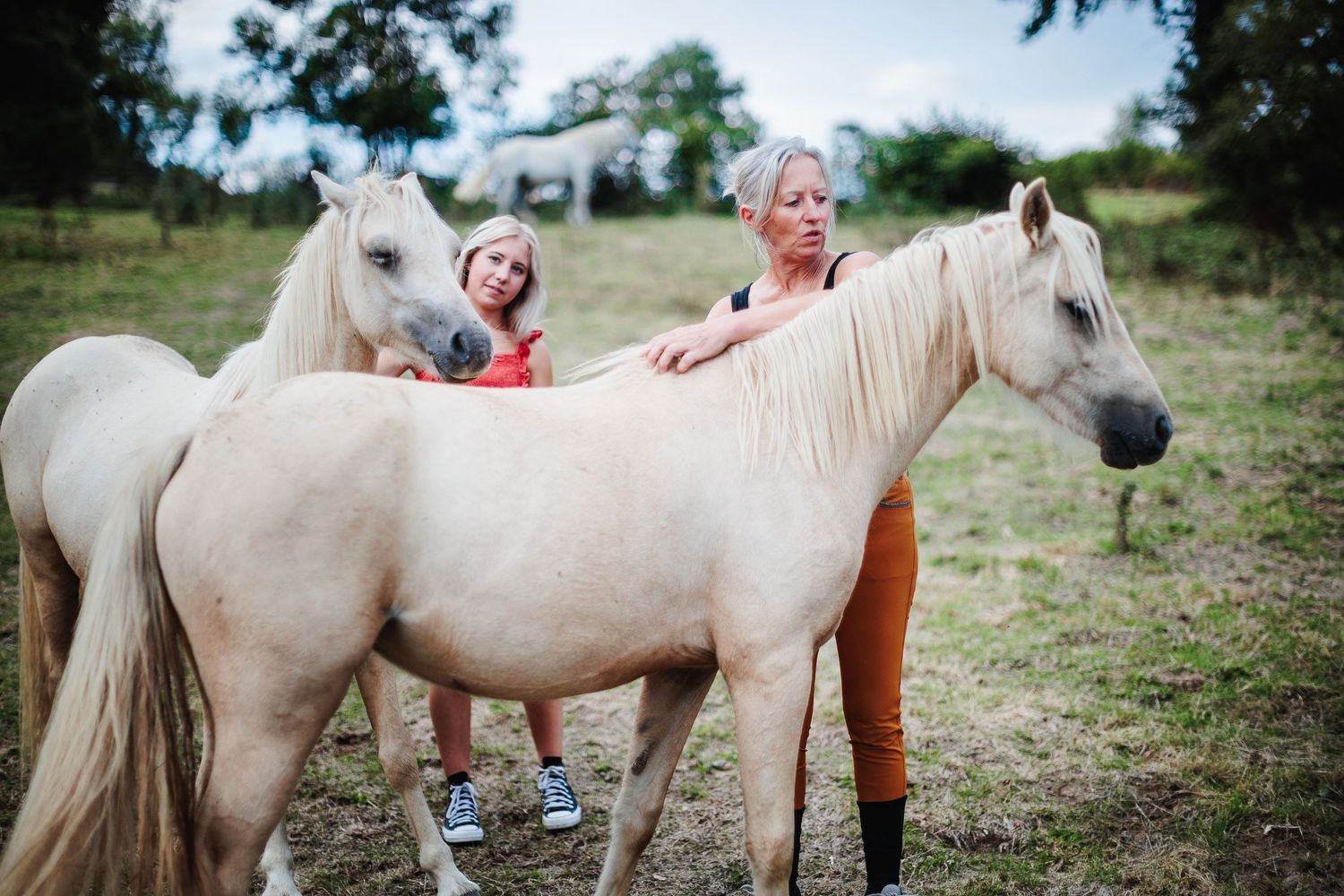 Mère et fille en interaction. Regards et caresses connectent la famille dans une passion équestre authentique, saisie par Eric Filliat.