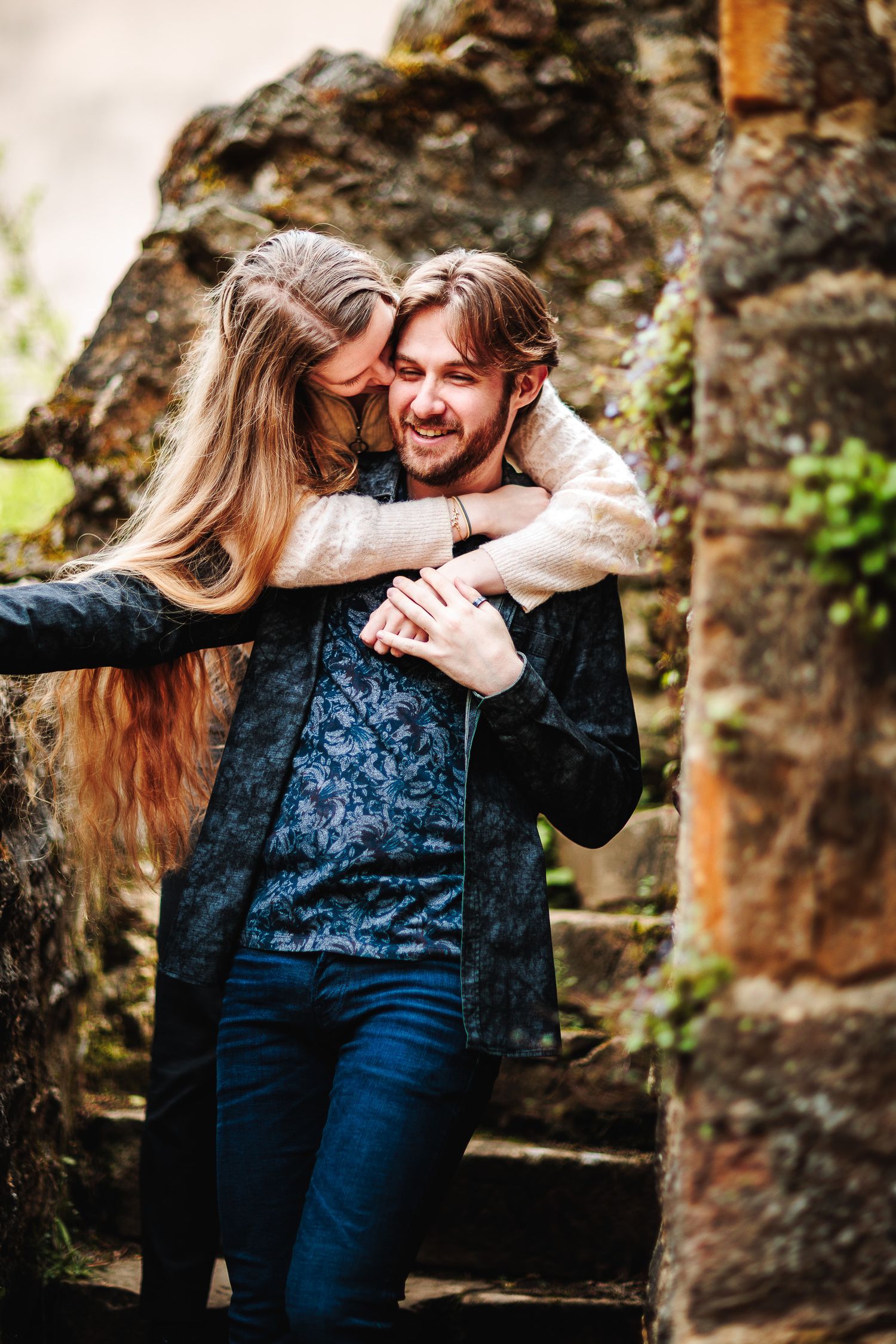 Fiancée enlacant vigoureusement son homme par derrière dans un décor de ruines de château, complicité et joie par Eric Filliat. Vers Tarare