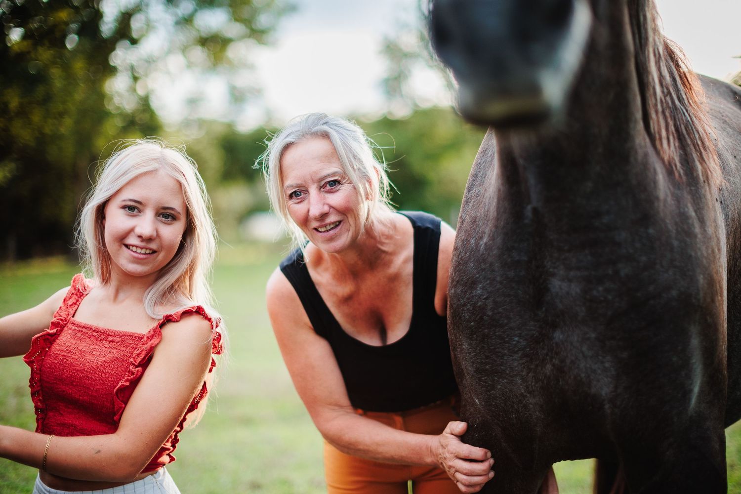Mère et fille souriantes avec leur cheval. Famille : connexion intense & complicité animale. Séance photo 